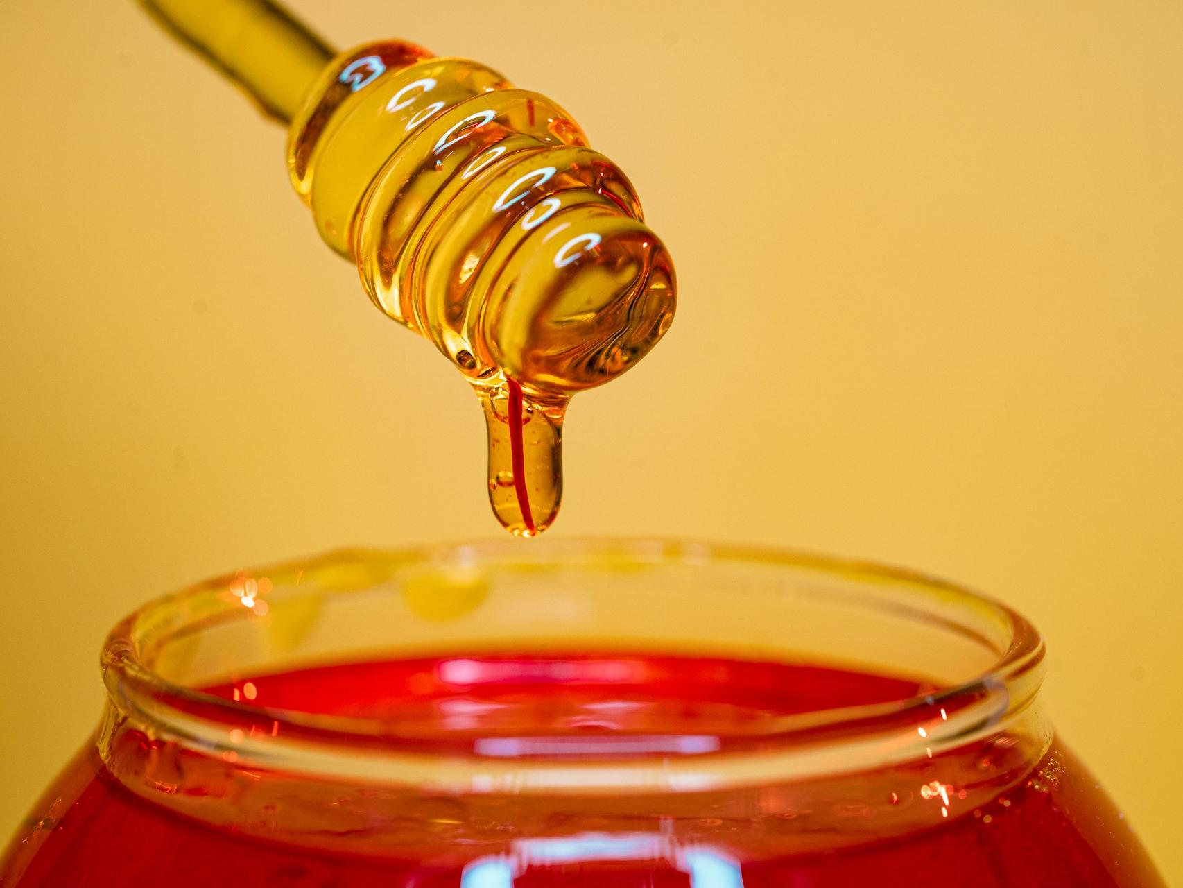 clear glass bottle pouring red liquid on clear drinking glass